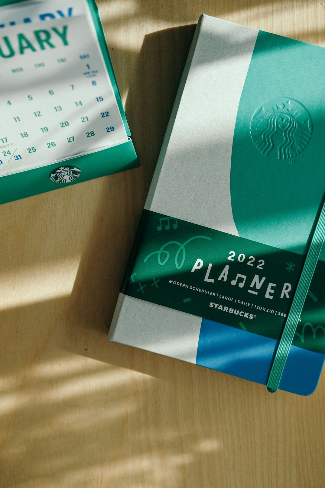 Desk planner calendar and a cup of coffee next to a laptop